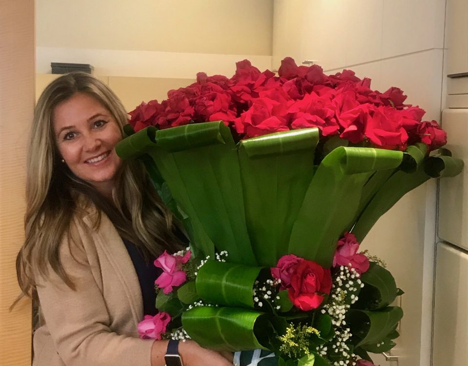 Trisha Webber holding a humongous bouquet of red roses