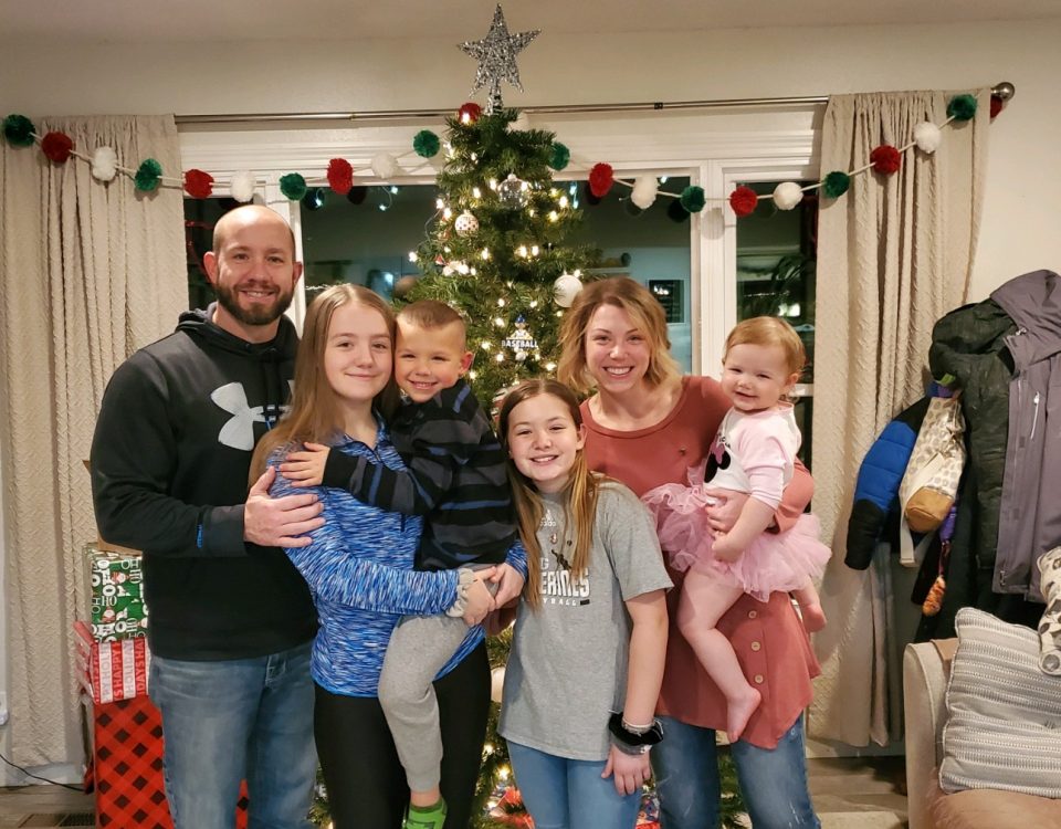 Kate and her family in front of the Christmas tree with presents under it