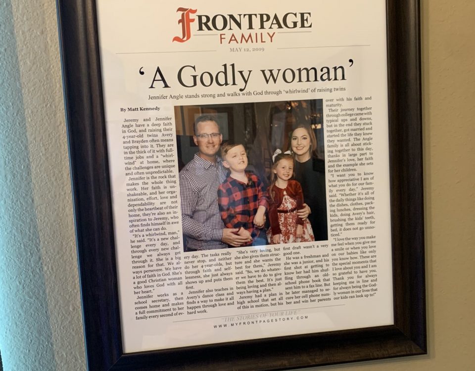 Personalized newspaper story titled 'A Godly Woman' hanging on the wall in a frame