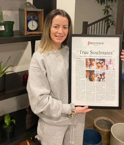 a woman holding a framed newspaper story titled 'True Soulmates'