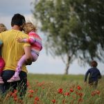 father holding his two daughters in a field - happy (early) Father's Day