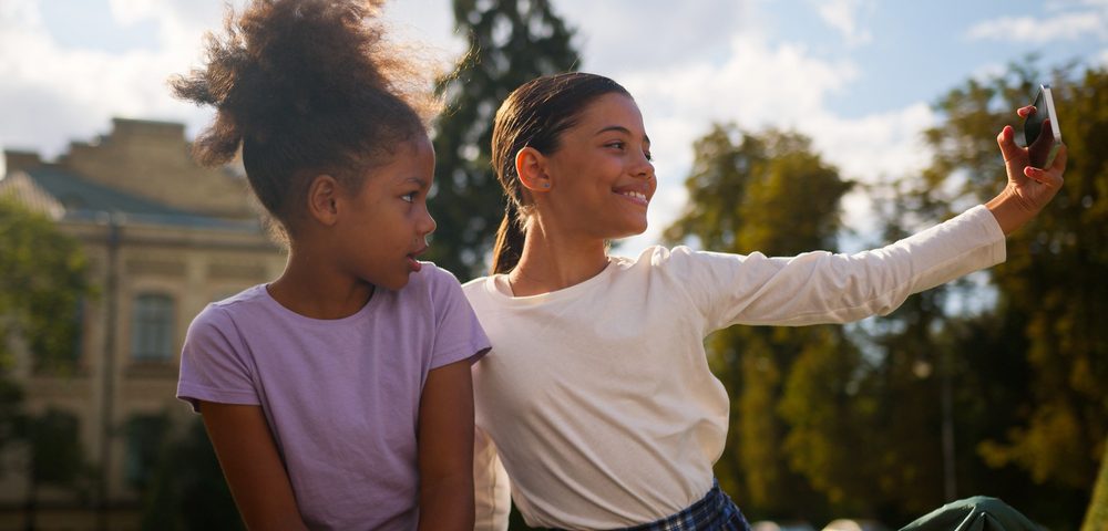 School study elementary education outdoors photo video vlog selfie posing happy little girls classmates students kids children female schoolgirls multiethnic African pupils using phone addicted blog — Call Recording and Kids blog post - two kids taking a selfie