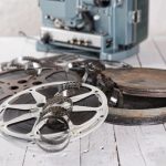 Evolution of Film blog post - Films and reels - several films and coils placed on an old white wooden table